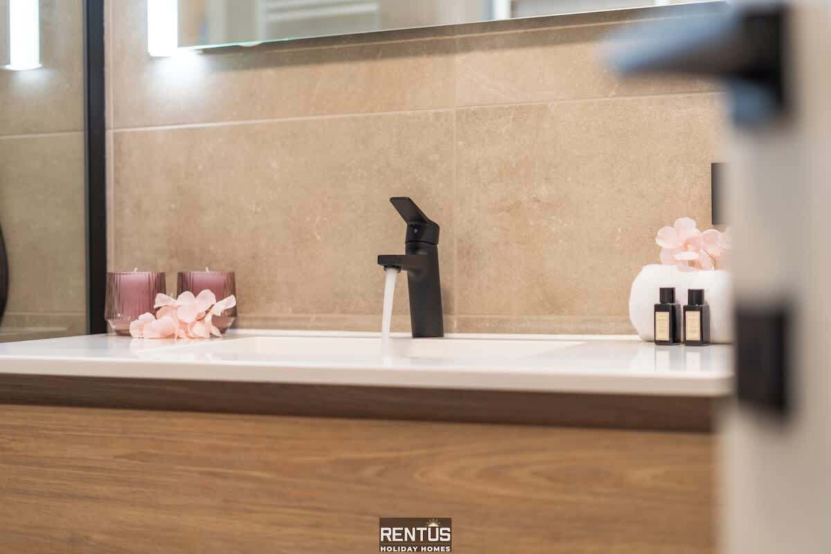 Ein Badezimmer mit einem modernen Waschbecken, einem Spiegel und einer Holzausziehtafel.