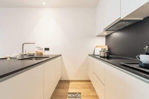 Eine moderne Küche mit schwarzem Arbeitsplatz, weißen Schränken und einer Edelstahl-Spüle.