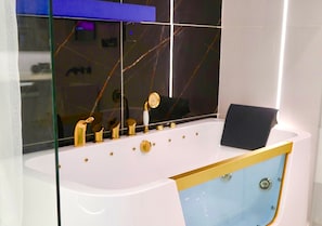 Een moderne badkamer met een wit bad, gouden details en een blauwe accentmuur.
