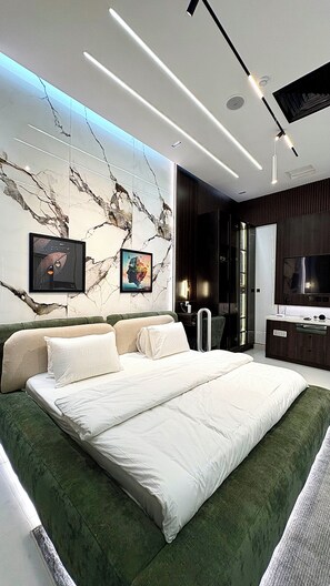 Een moderne slaapkamer met een groot bed, een flatscreen televisie en een wand met een marmerlook.