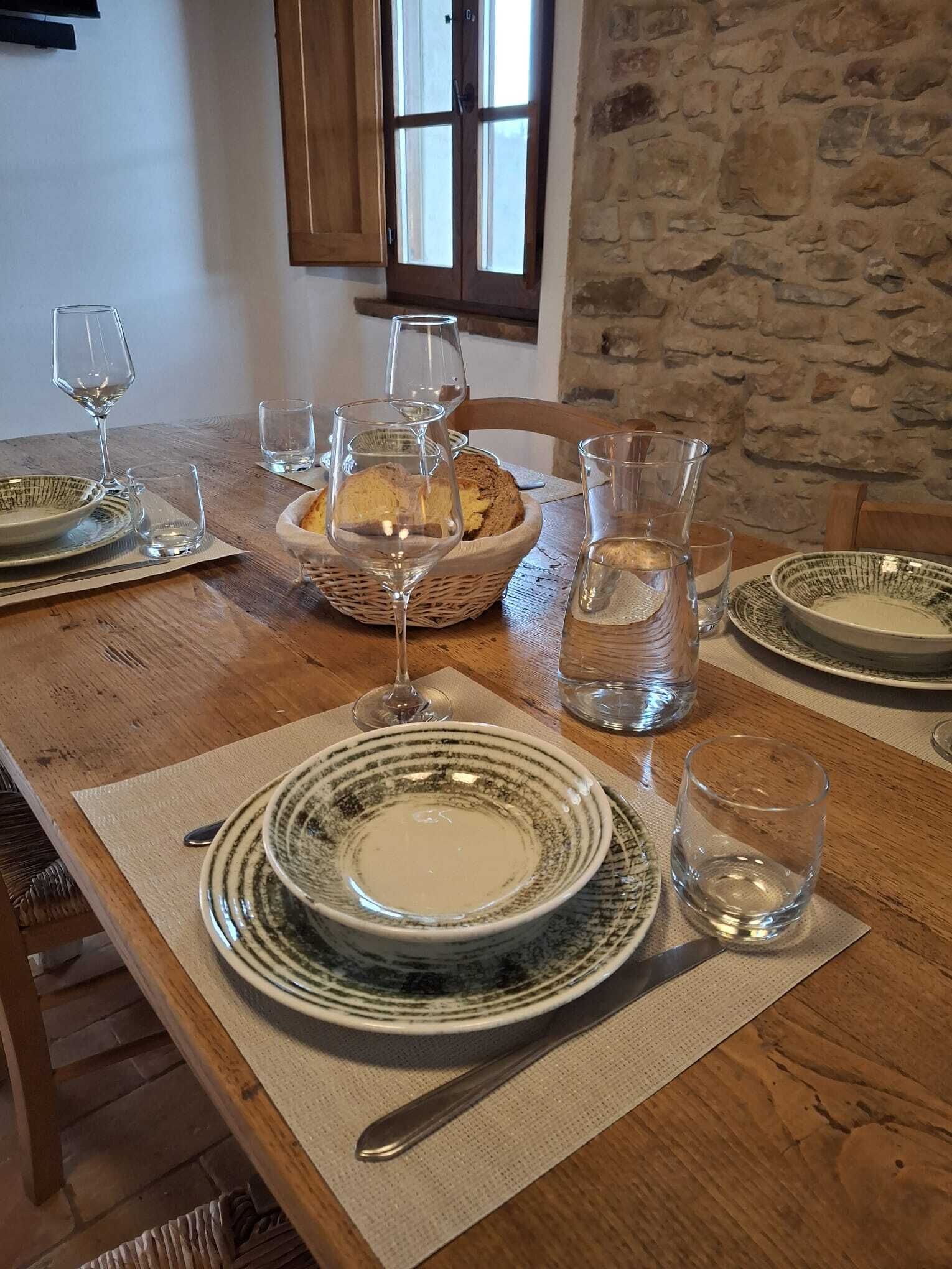 Une table à manger dressée avec des assiettes, des verres et un panier de pain.