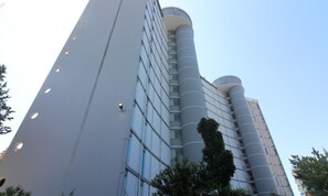Un bâtiment moderne au design cylindrique original, doté de grandes fenêtres et d’une structure verticale imposante.