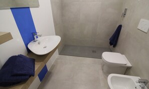 A bathroom with a white sink, a toilet, and a shower area. - Flat on the shores of Lignano (Lignano Sabbiadoro)