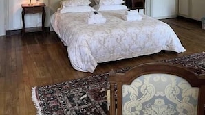 A bedroom with a large bed, a chandelier, a nightstand, and a patterned wall.