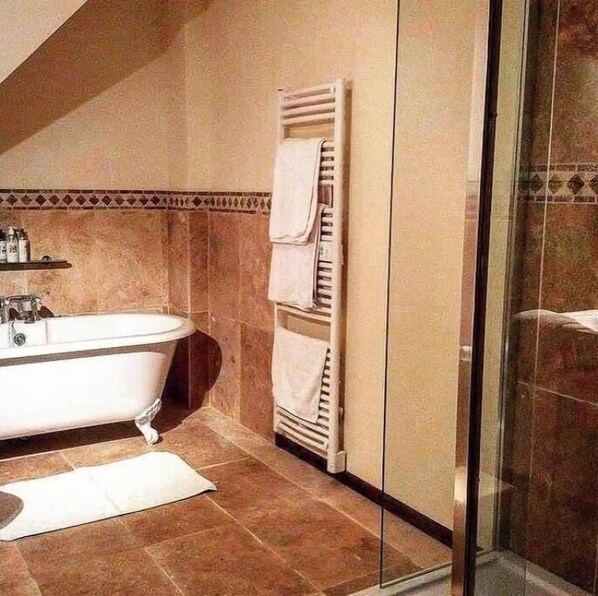 A bathroom with a freestanding bathtub, a towel rack, and a glass shower enclosure.