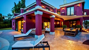 Una casa moderna con patio, completa di poltrone relax e tavolo da pranzo.