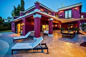 A modern house with a patio area featuring lounge chairs and a dining table. - Villa Sunsets - charming villa in residential area in Elviria (Marbella)