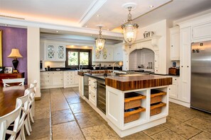 A spacious kitchen with white cabinetry, a central island, and a stainless steel refrigerator. - Villa Sunsets - charming villa in residential area in Elviria (Marbella)