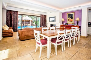 A spacious living area with a large dining table, comfortable seating, and a view of a swimming pool. - Villa Sunsets - charming villa in residential area in Elviria (Marbella)