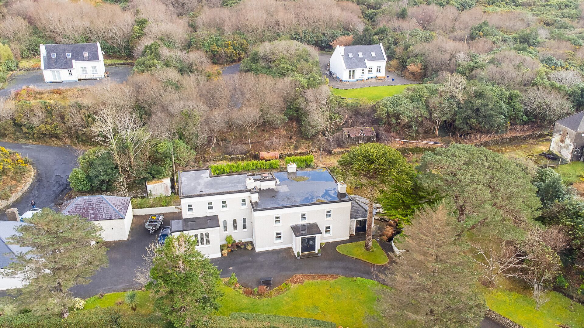 Une grande maison à deux étages, dotée d’un vaste jardin devant et d’une allée menant à un garage.