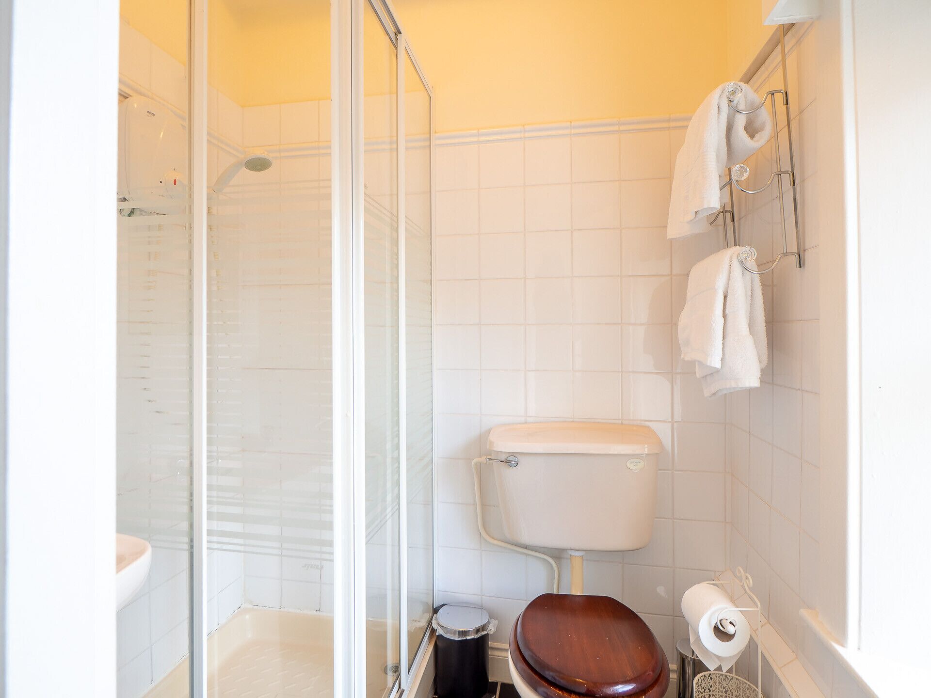 Ein kleines, modernes Badezimmer mit einer gläsernen Duschkabine, Toilette und Waschbecken.