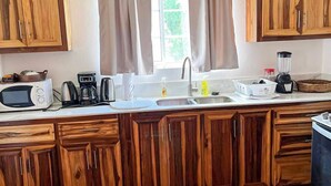 Una cucina con mobili in legno, un forno a microonde, una macchina per caffè e un frullatore.