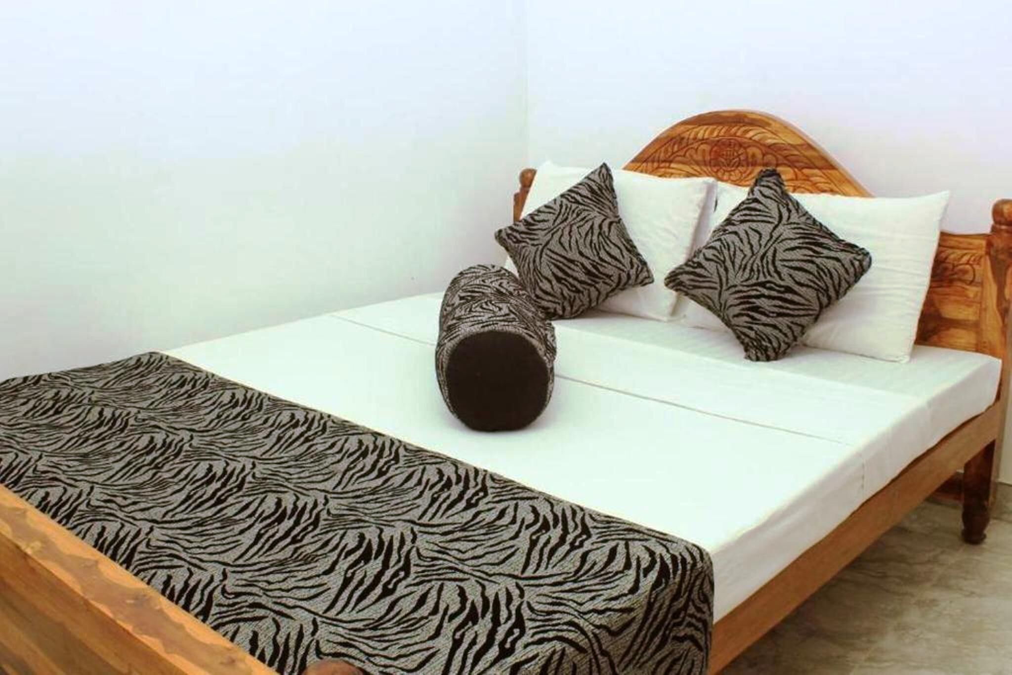 A bed with a zebra-patterned bedspread, two tiger-patterned pillows, and a wooden headboard.