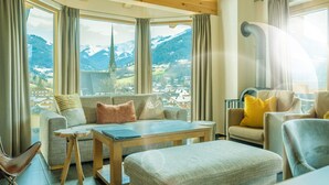 A cozy living room with a sofa, armchairs, a coffee table, and a view of a mountain town. - eder.VIEW (Maria Alm am Steinernen Meer)