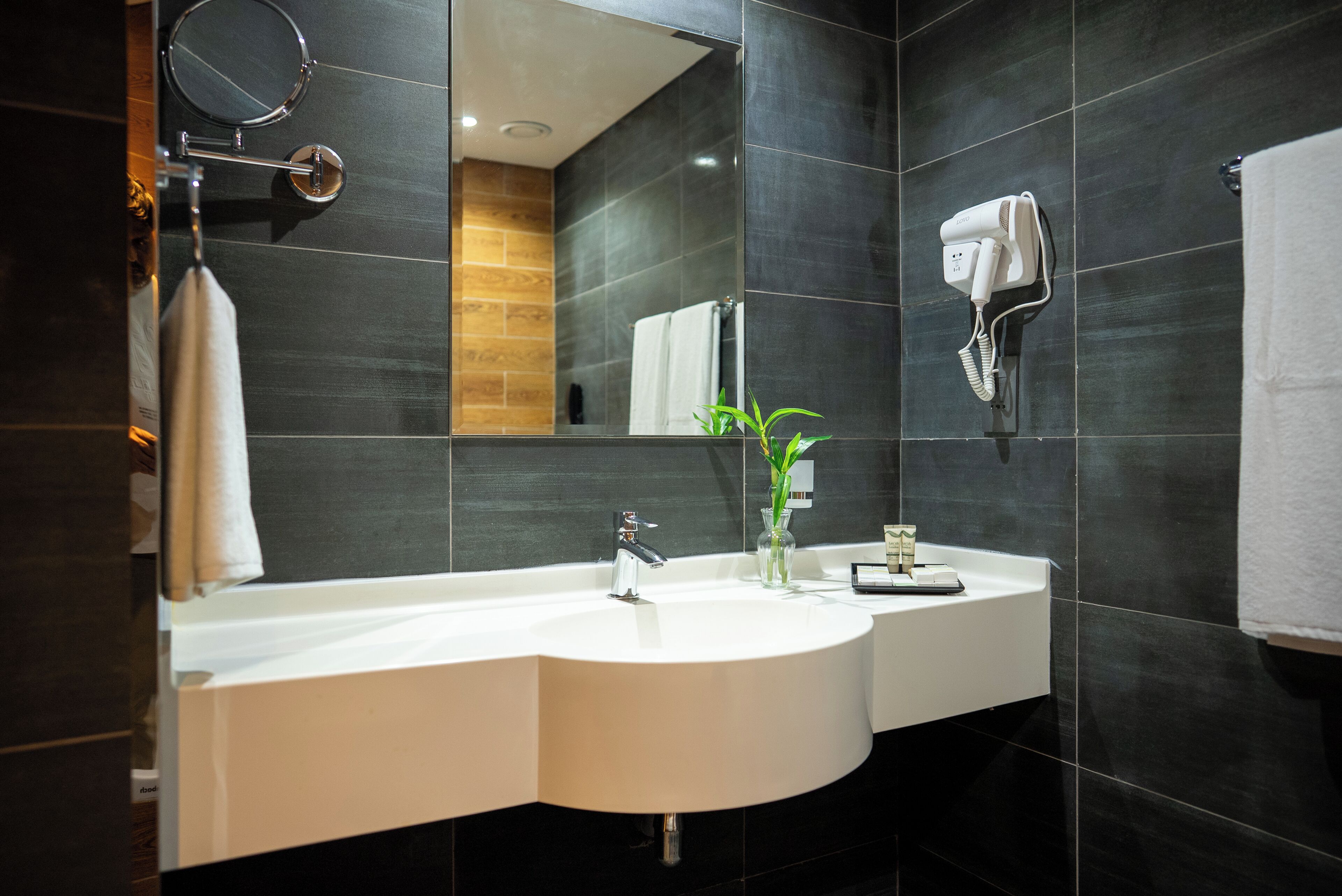 A modern bathroom with a double sink, a hairdryer, and a mirror.