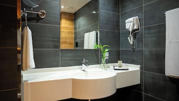 A modern bathroom with a double sink, a hairdryer, and a mirror.