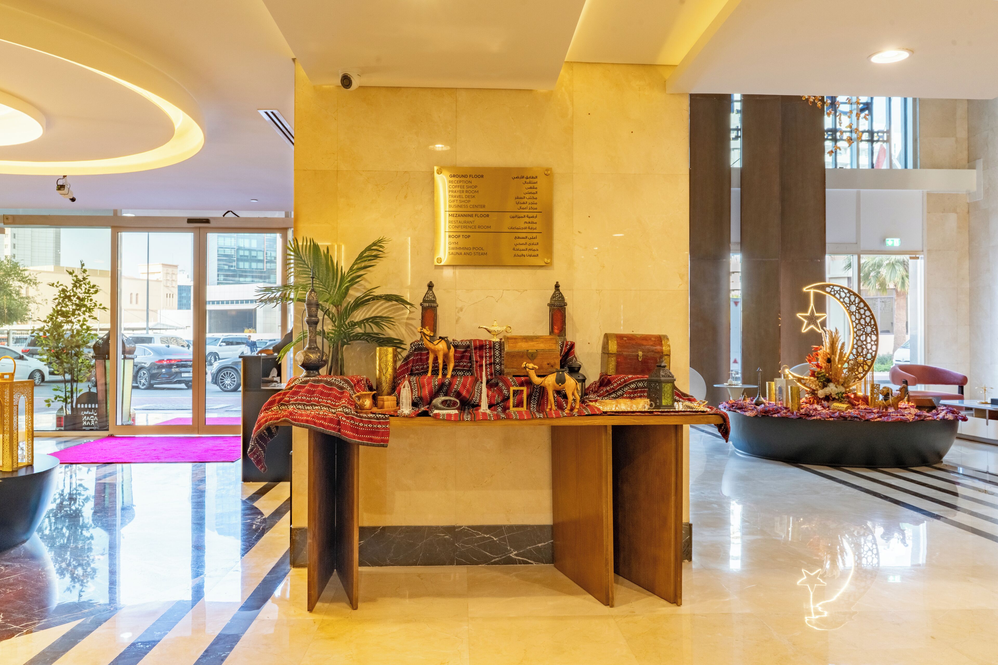 A reception desk with a marble floor, a sign listing hotel floors, and a decorative plant.