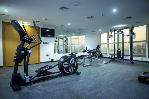 A gym with exercise equipment, large windows, and a wooden door.
