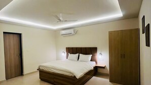 A modern bedroom with a large bed, a ceiling fan, recessed lighting, and a wardrobe. - Greek House By Housiify (Gurugram)