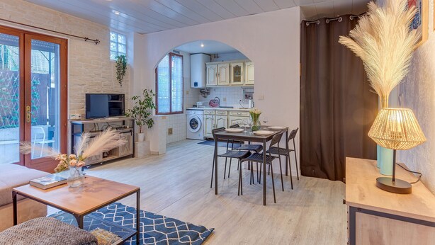 Een moderne keuken met witte kasten, een eethoek met een tafel en stoelen, en een woonkamer met een bank en salontafel.