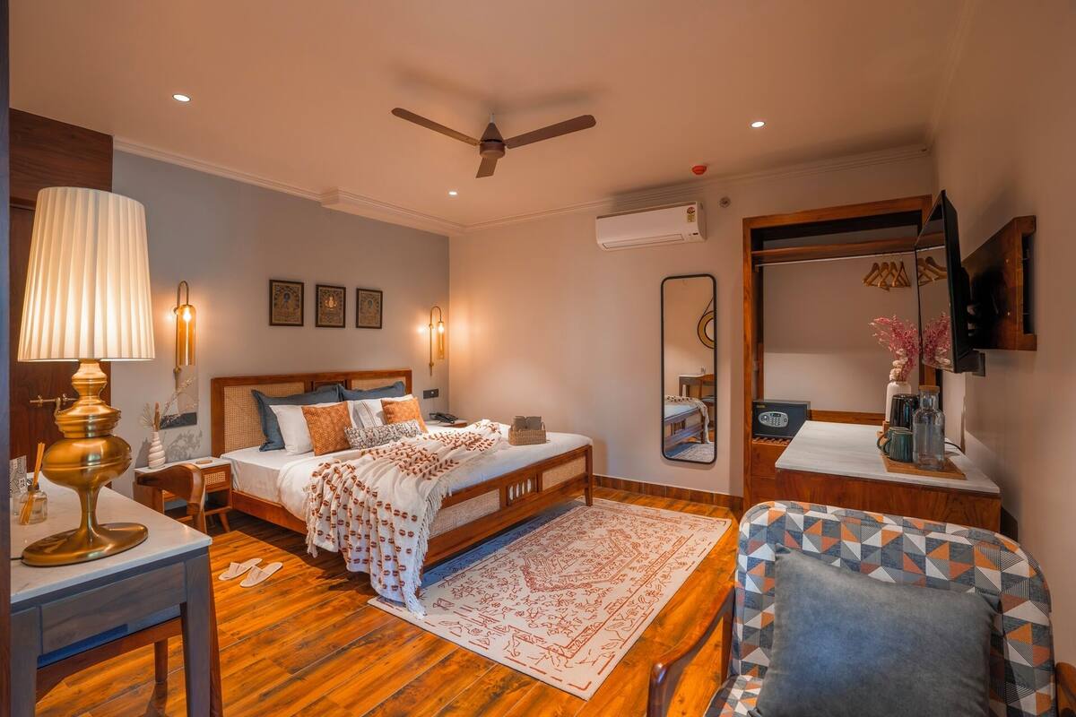 Ein Schlafzimmer mit Bett, Nachttischen, Schreibtisch, Stuhl, Deckenventilator, Klimaanlage und Spiegel.