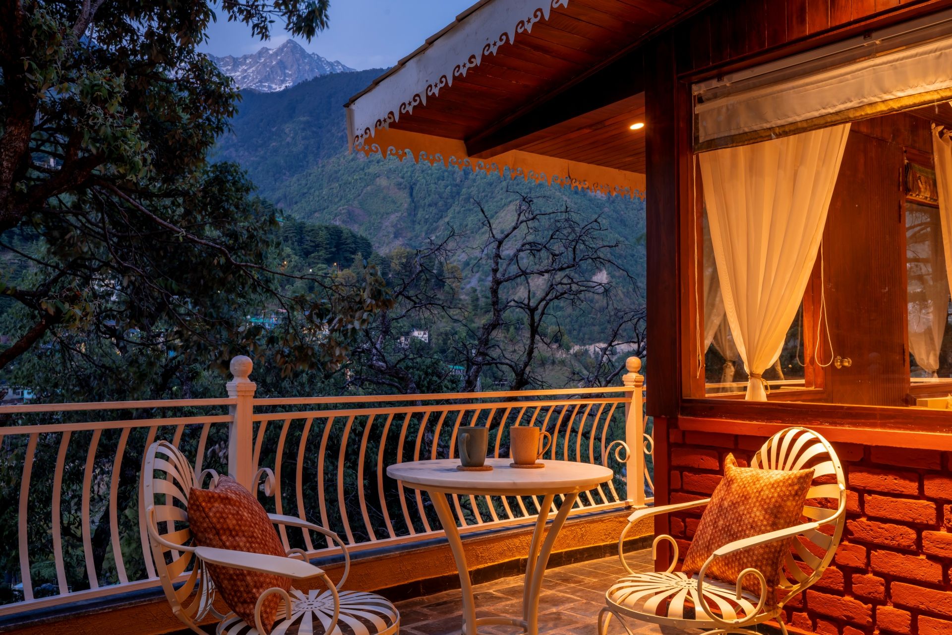 Un balcon avec deux chaises et une table, donnant sur un paysage montagneux.
