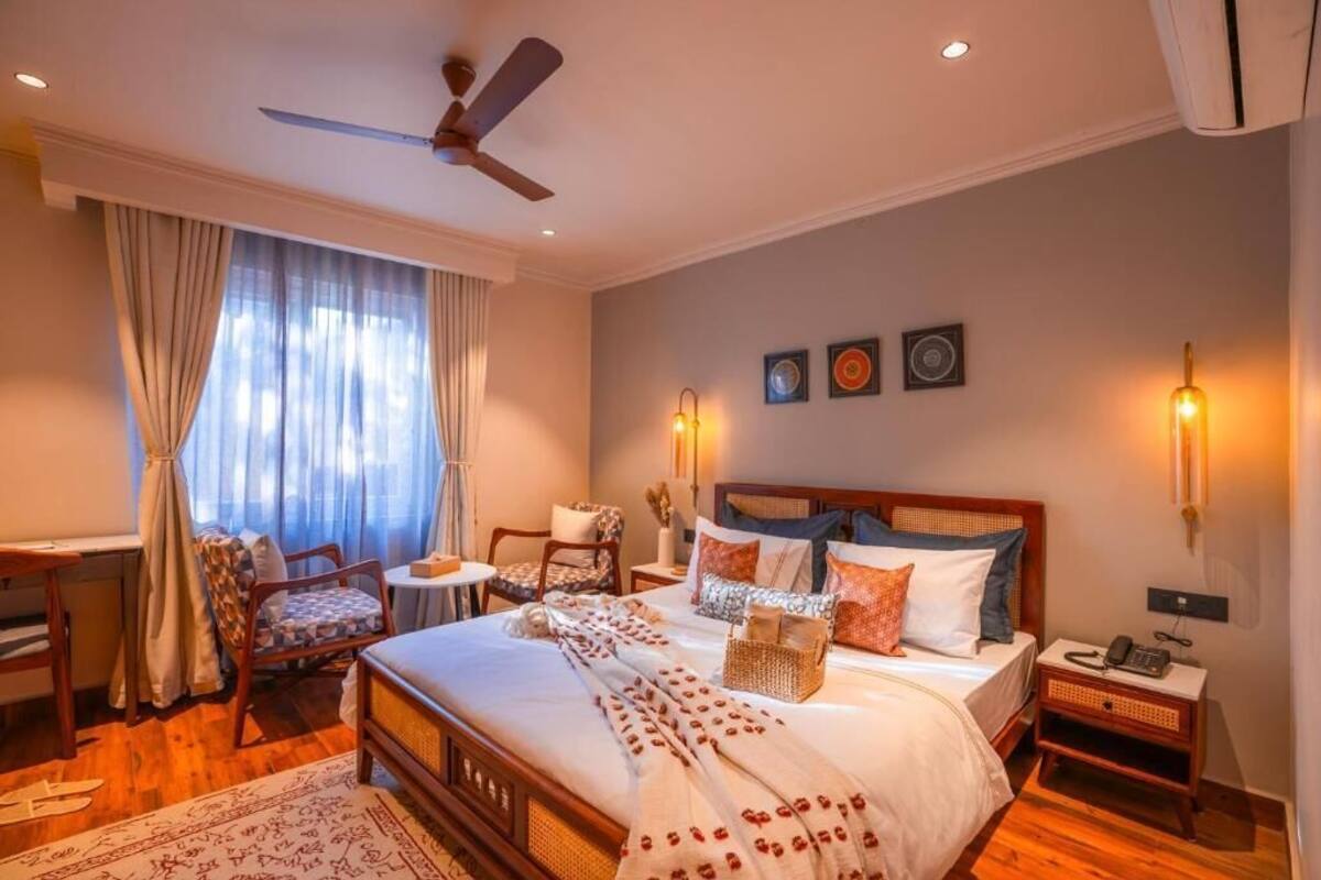 Ein helles Schlafzimmer mit einem großen Bett, einem Deckenventilator, einem Schreibtisch und einem Stuhl.