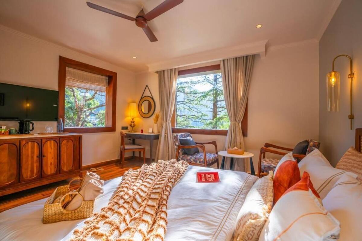 Ein Schlafzimmer mit Bett, Schreibtisch, Stuhl, kleinem Tisch und Fernseher an der Wand.