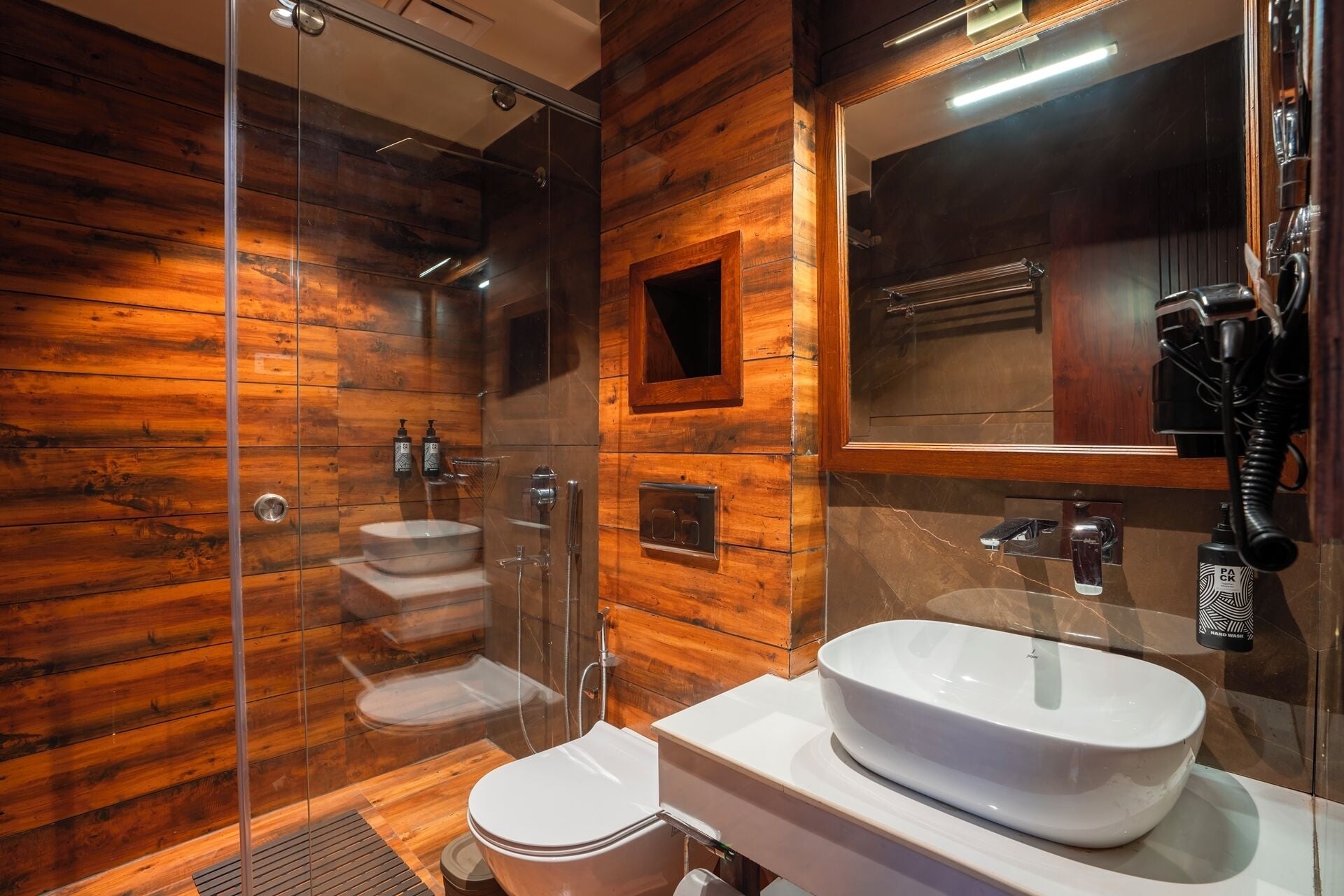 A modern bathroom with a glass shower enclosure, a white sink, and a toilet.