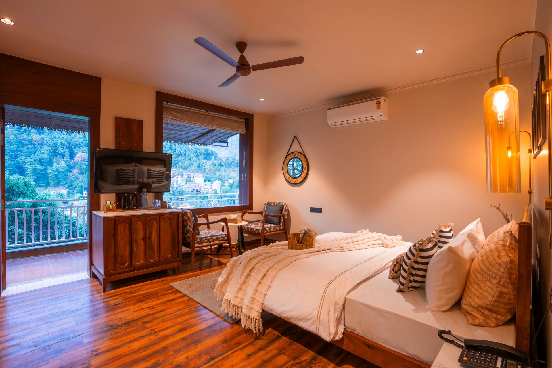 A bedroom with a bed, a desk, a chair, a television, and a view of the outdoors.