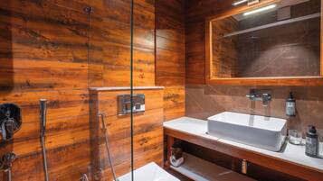 Un baño con paredes de madera, un lavamanos blanco, un espejo y una ducha.