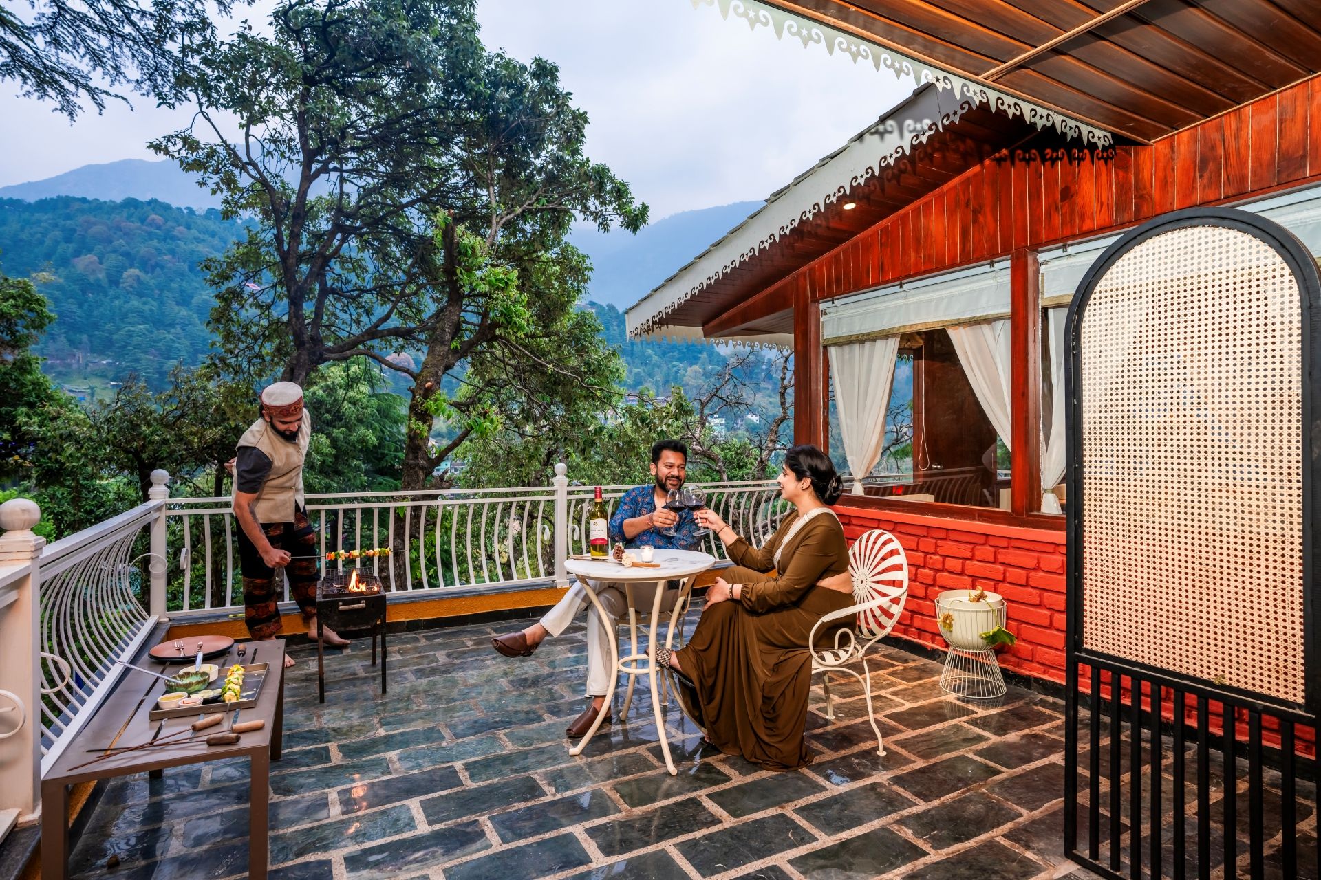 Une terrasse avec une table et des chaises, un barbecue et une vue sur les montagnes.