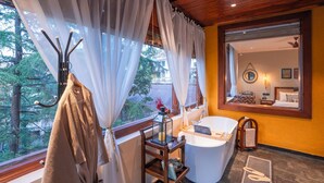 Ein Badezimmer mit Badewanne, Spiegel und Blick ins Freie.