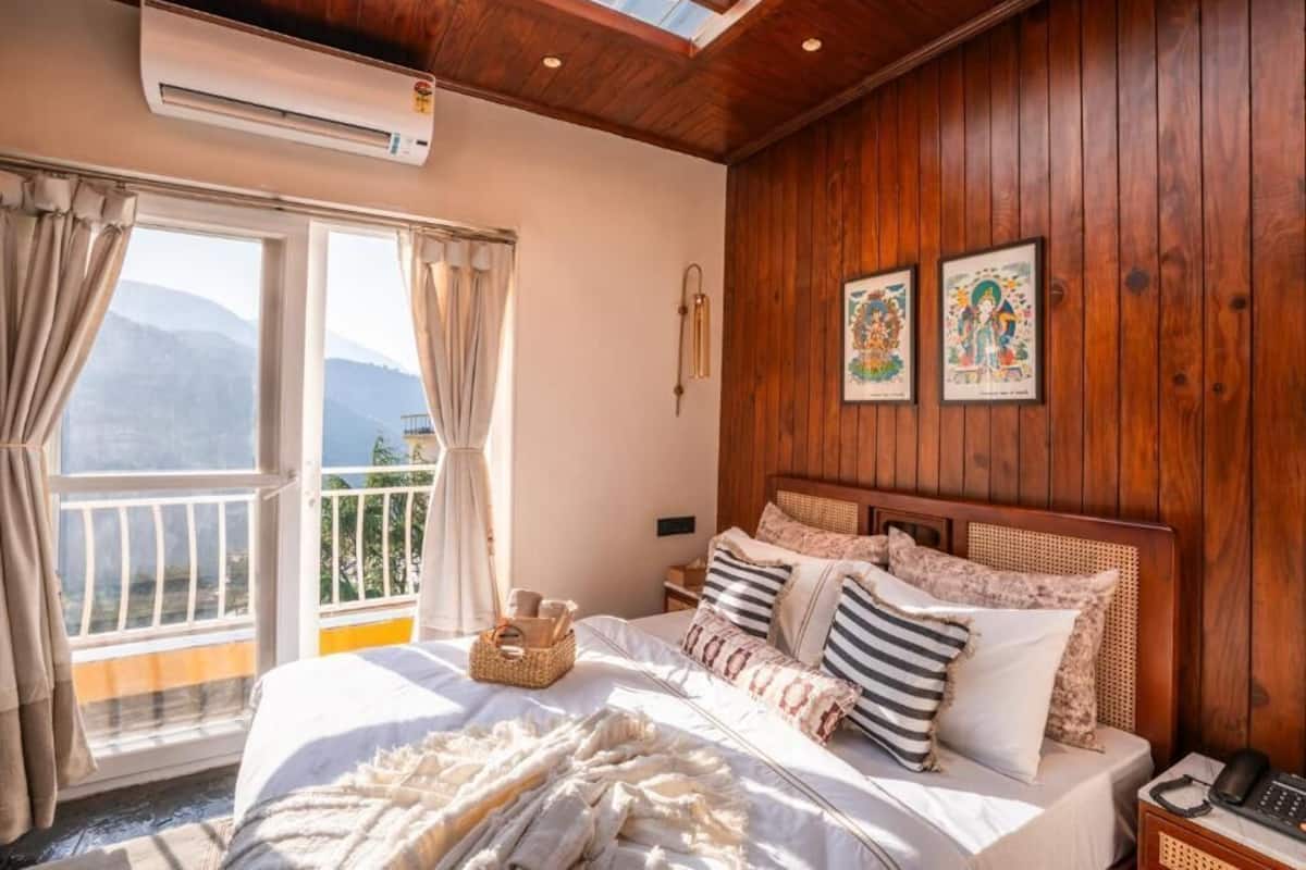 Ein Schlafzimmer mit einem Bett, einem Nachttisch, einem Telefon und einem Fenster mit Vorhängen.