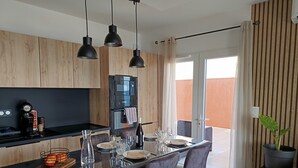 Una cocina moderna con armarios de madera, encimera negra y una zona de comedor con mesa y sillas.