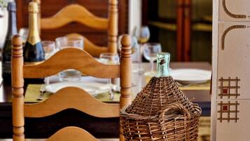 A dining table with chairs, a wicker basket, and a bottle.