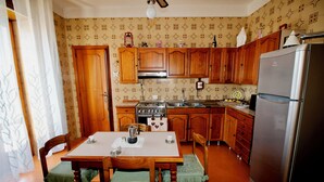 A kitchen with wooden cabinets, a stainless steel refrigerator, and a dining table with chairs.
