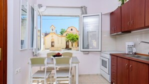 Cocina compacta con comedor, vista a un edificio con campanario y cafetera en la encimera.