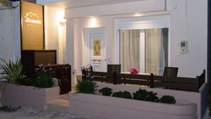 Exterior moderno de un hotel con una recepción, un banco y un pequeño jardín con plantas.