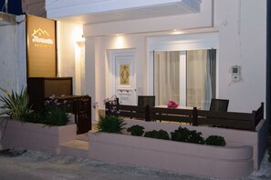 Ein modernes Hotelgebäude mit Empfangsbereich, einer Bank und einem kleinen Garten mit Pflanzen.
