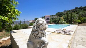 En staty föreställande en lejon i sten, placerad nära en swimmingpool med utsikt över hus och träd.