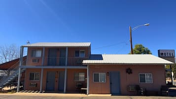 A two-story motel with a balcony on the upper floor, a sign reading "Travelers Motel," and a small porch area with a bench.