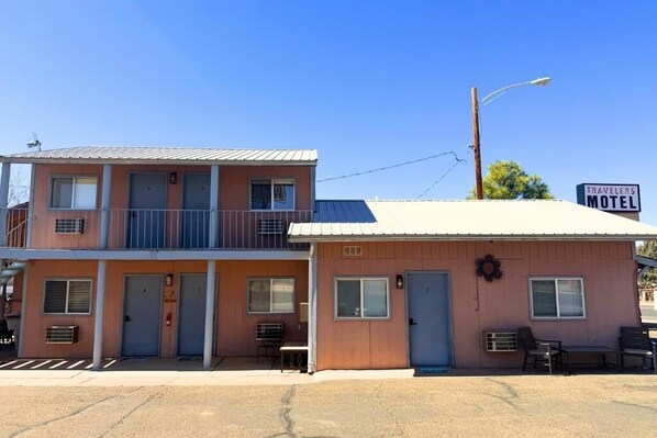 A motel with a two-story building, a balcony on the upper floor, and a small porch area with seating. - Travelers Motel (Kanab)