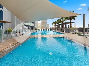 A swimming pool with a modern design, surrounded by lounge chairs and a covered area. - Bloomfields Stunning STU Bloom Tower JVC (Dubai)