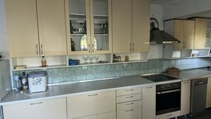 A kitchen with beige cabinets, a stainless steel range hood, a dishwasher, and a built-in oven.