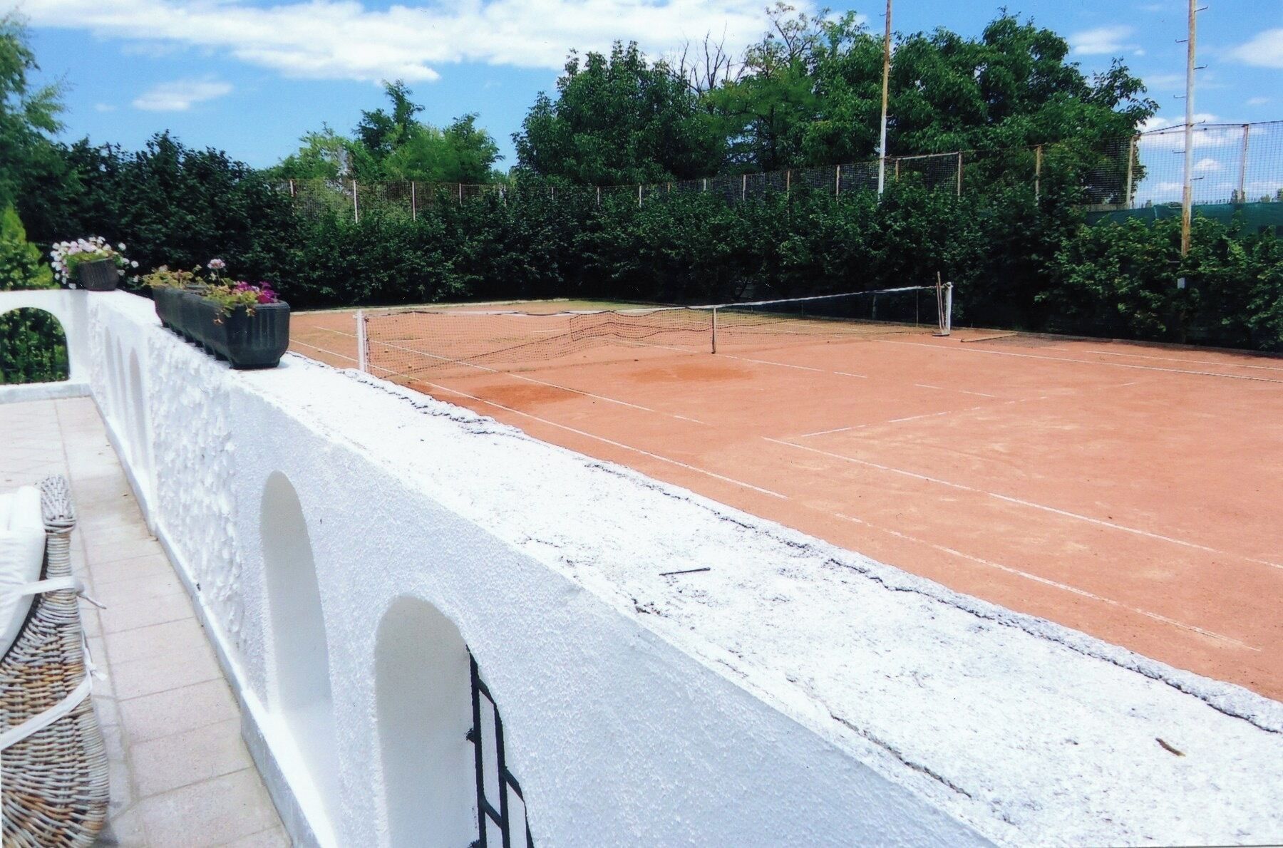En tennisbane med hvid mur og net.