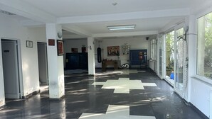 A hallway with a checkered floor pattern, white walls, and a large window on the right.