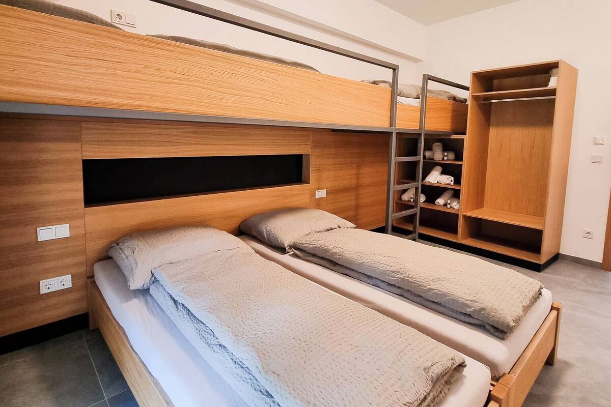 A bunk bed room with a wooden headboard, a wardrobe, and a ceiling light.