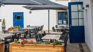 An outdoor seating area with tables and chairs, a blue door, and a sign reading "Batin Rackesmillen". - Rackésmillen (Enscherange)