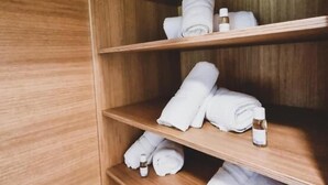 A wooden shelf with neatly folded towels and small bottles, likely containing toiletries. - Rackésmillen (Enscherange)